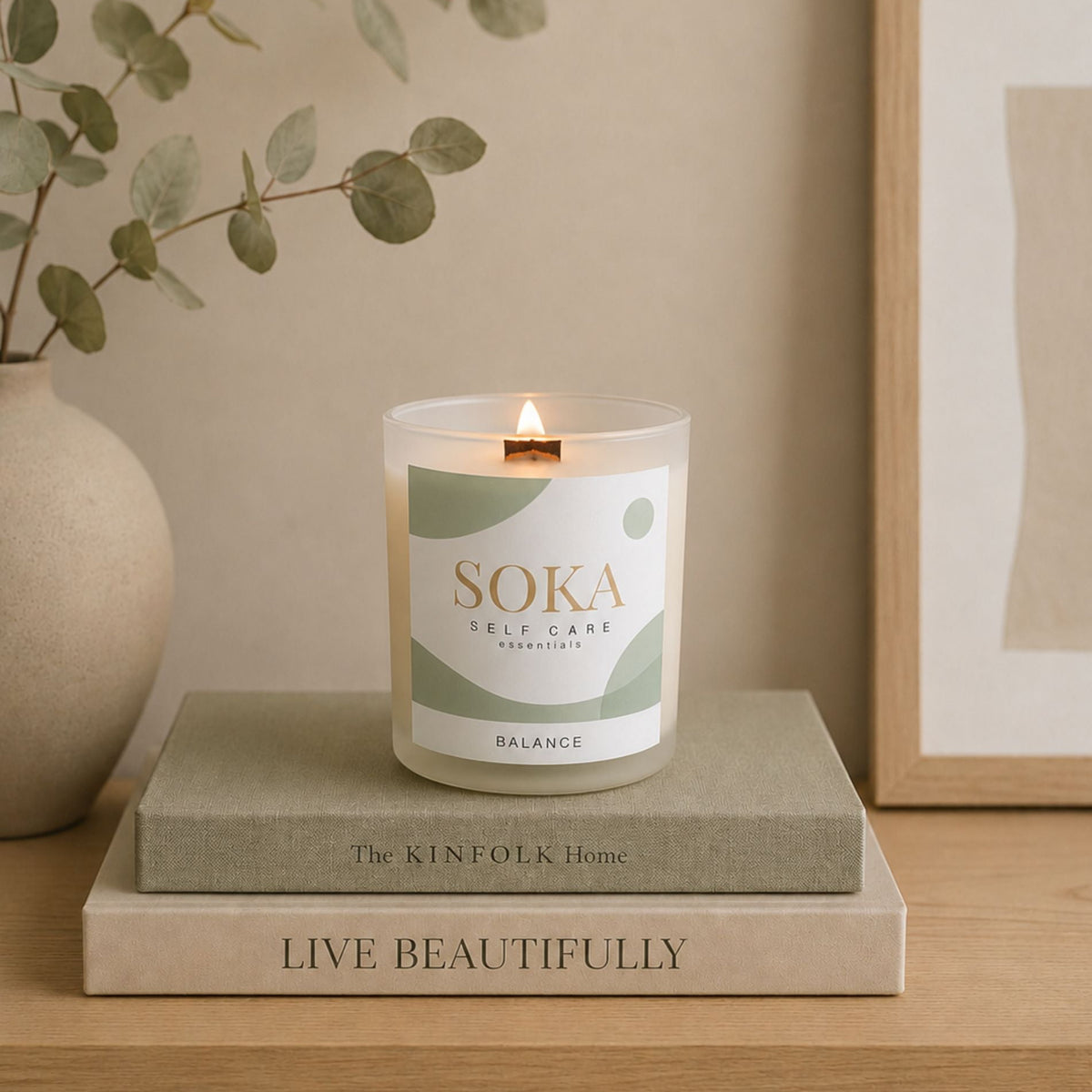BALANCE Soka candle on a book with a plant and framed picture in the background