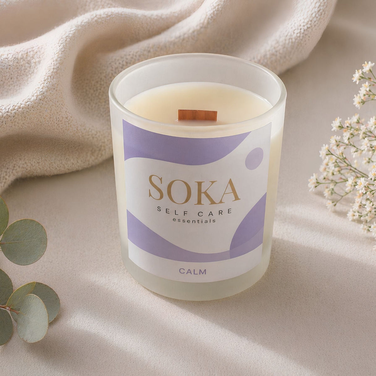 CALM Soka self-care candle on a soft surface with eucalyptus and baby's breath