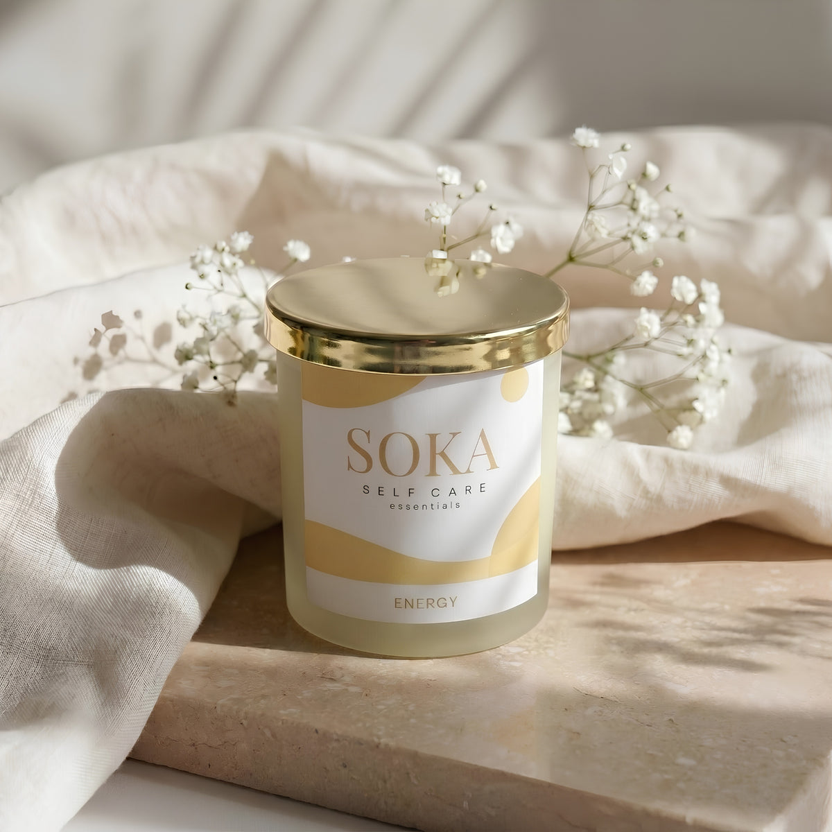 ENERGY SOKA self-care candle on a stone surface with baby's breath flowers and neutral background