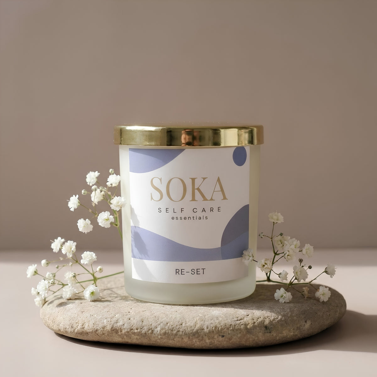 RE-SET SOKA self-care candle on a stone surface with baby's breath flowers and neutral background