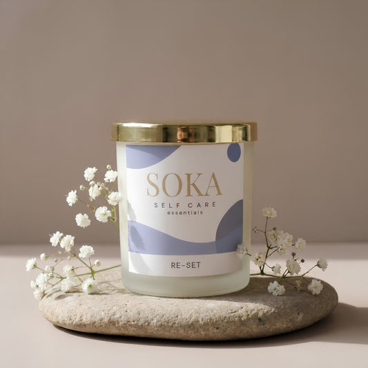 RE-SET SOKA self-care candle on a stone surface with baby's breath flowers and neutral background